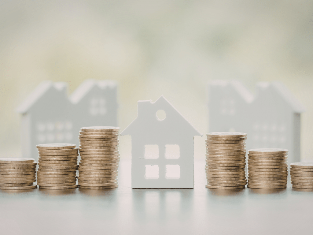 Investir dans l’immobilier en 2026 : illustration du rendement net avec piles de pièces et maisons miniatures pour évaluer la rentabilité
